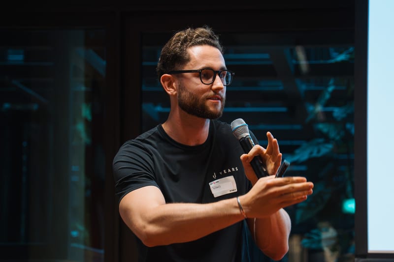Niko Hems giving a keynote, holding a microphone mid-gesture