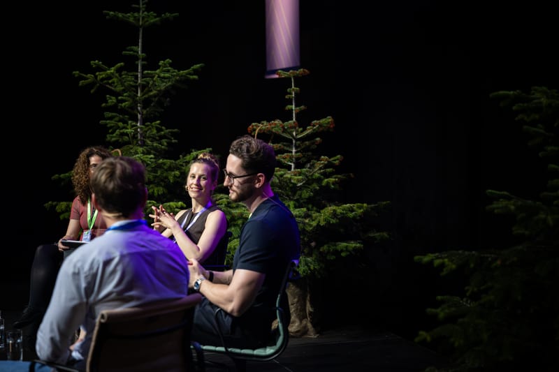 Niko Hems in a small-group discussion on stage, talking with other participants